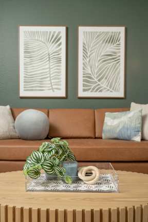 A living room with a couch, a coffee table, and two framed artworks on the wall.