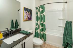 A bathroom with a green towel and a green shower curtain.