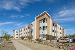 A modern apartment building with a parking lot in front.