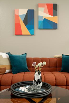A living room with a red couch and two abstract paintings on the wall.