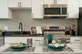 A modern kitchen with a black countertop and white cabinets.