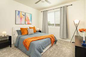 A bedroom with a bed, nightstand, and two paintings on the wall.