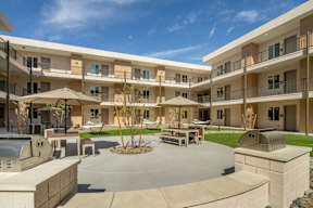 A courtyard with a fire pit and seating area in front of apartment buildings.