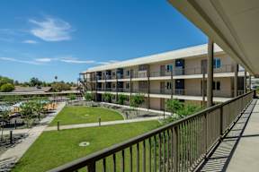 A view of a building with a balcony overlooking a green lawn.
