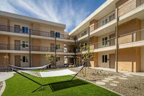 A hammock is strung between two balconies on a sunny day.