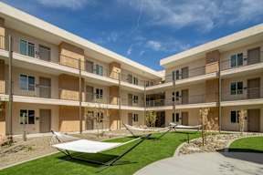 A sunny day at a modern apartment complex with a hammock in the courtyard.