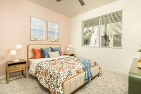 A bedroom with a bed, nightstand, and two windows.