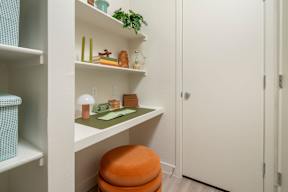 A white shelf with a green plant and some objects on it.