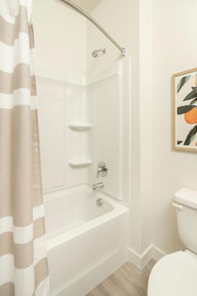 A white bathroom with a striped shower curtain.