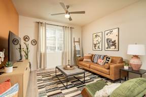 A living room with a brown couch, a coffee table, and a television.