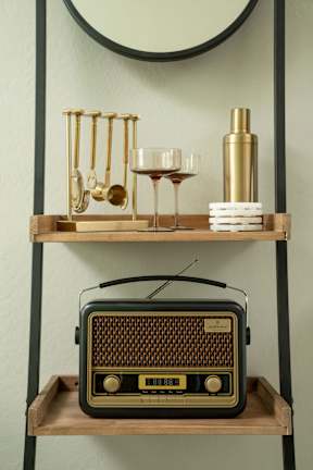 A shelf with a radio, wine glasses, and a bottle.
