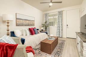 A living room with a white couch, a red blanket, and a painting on the wall.
