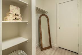 A white shelf with a stack of boxes on it and a mirror leaning against the wall.