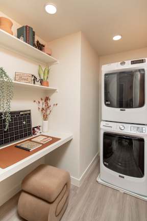 A modern kitchen with a white oven and a wooden shelf.