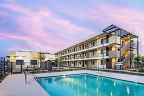 A modern apartment complex with a swimming pool in the foreground.