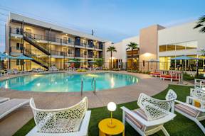 A pool area with chairs and a building in the background.