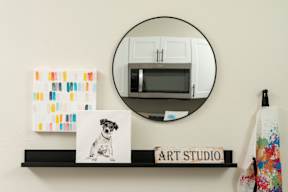 A picture of a dog is on a shelf under a mirror.