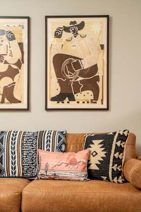 A living room with a couch and two framed artworks on the wall.