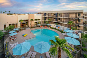 A pool surrounded by palm trees and umbrellas.