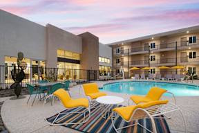 A poolside area with yellow chairs and a white table.