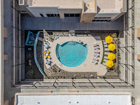 A small pool surrounded by a concrete patio and yellow chairs.
