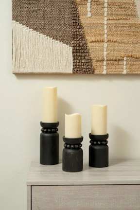 Three candles are lit and placed on a dresser.