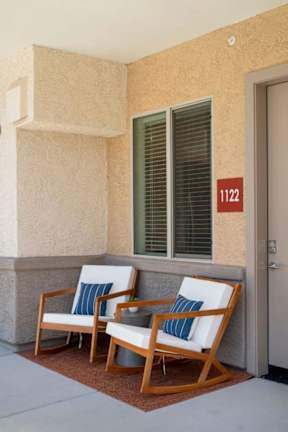 Two chairs are placed on a patio in front of a wall with a number 112 on it.