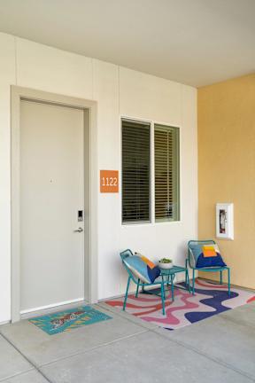 A white door with a number 1122 on the wall next to a window.