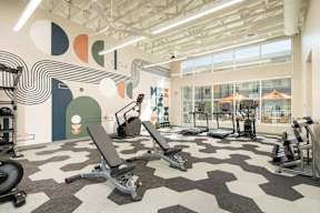 A gym with a variety of equipment including treadmills, weights, and exercise machines.
