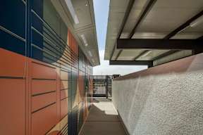 A long hallway with a white wall on the right and a wall with orange and blue on the left.