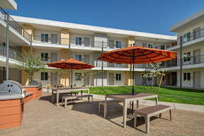A patio with a table and chairs and an umbrella.