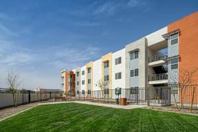 A modern apartment complex with a green lawn in front.