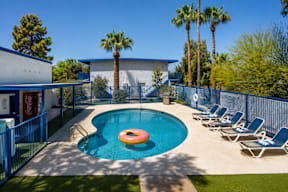 A pool with a blue fence and a red inflatable ring.