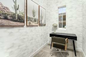 A room with a black desk and a cactus print on the wall.