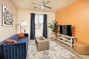 A living room with a blue couch, a television, and a ceiling fan.