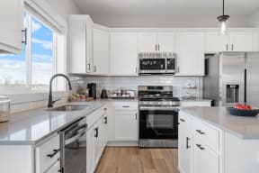 a large white kitchen with stainless steel appliances and white cabinets