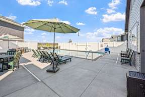 A patio with a green umbrella and chairs.