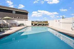 A large swimming pool with a white fence and a building in the background.
