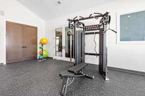 A gym with a weight machine, a bench, and a ball.