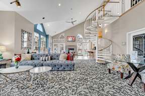 A living room with a spiral staircase and a grey sofa.