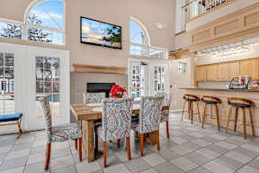 A dining room with a fireplace and a television mounted on the wall.