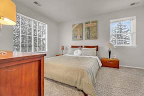 A bedroom with a bed, nightstand, and lamp.
