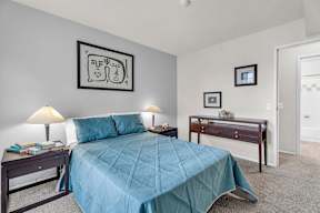 A bedroom with a bed, desk, and lamp.