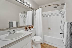 A white bathroom with a toilet, sink, and shower.