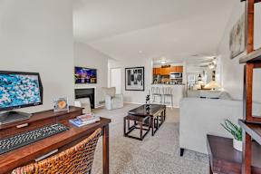 A living room with a white couch and a wooden desk.