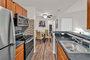 A kitchen with a refrigerator, sink, and dining table.