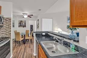 A kitchen with a stone wall and a dining table with chairs.