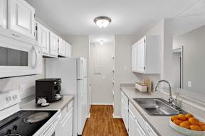 A kitchen with white appliances and wooden floors.