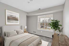 A bedroom with a large bed and a painting on the wall.