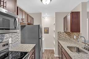 A kitchen with a stove top oven, microwave, refrigerator, and sink.